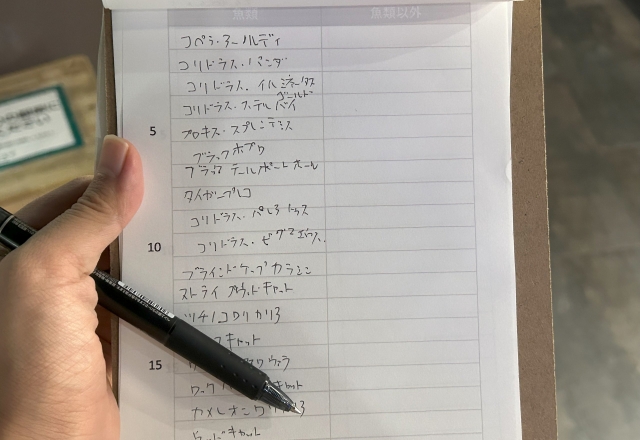 ボードに挟まった紙に種の名前を書き込んでいる様子。