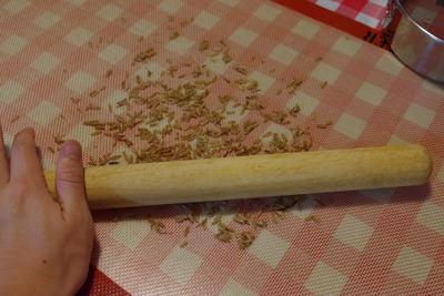 蒸したカラスムギを麺棒で押しつぶす。
