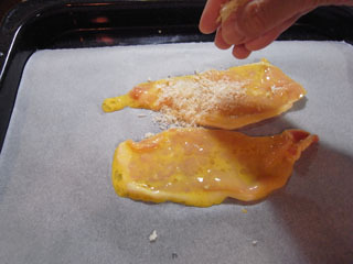卵に浸した薄切り豚肉を、シートを敷いた天板に乗せてパン粉をパラリ。