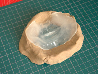 マスクから取った型を粘土で固定。これに着色した原液を流し込む。 