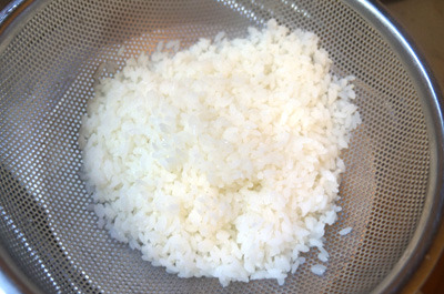 お米を茹でてざるに上げ、軽く水で洗う