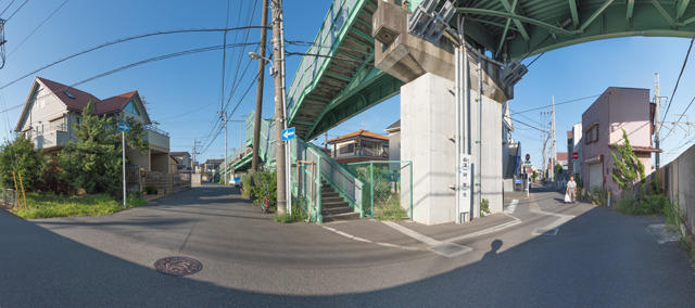 逆サイドから。画面右が線路。住宅街に佇む端麗な陸橋にもかかわらず、よく見るとその橋脚に立て看板が。