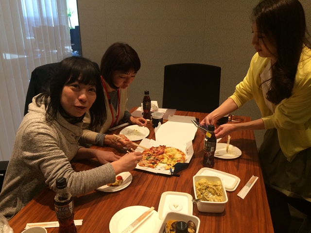 会議室で持ち寄りの料理と宅配ピザでワイワイしている女性たち