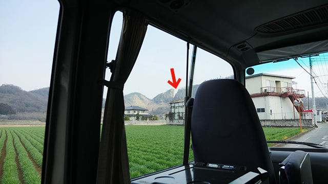 We see the Iwafune mountain direction from the bus.  The arrow shows that the mountain was cut in a V shape clearly at the 3.11 earthquake.
