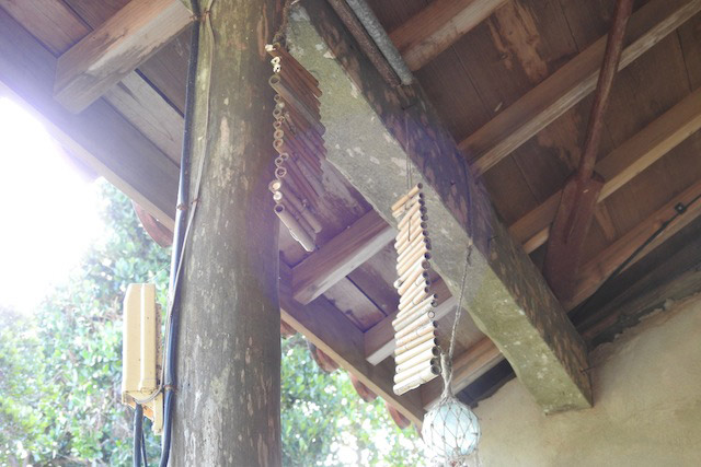軒下にはハチが巣を作る竹筒が下げてある。家の中に入ってくるのを殺さずに防ぐために保久村さんが用いた策。