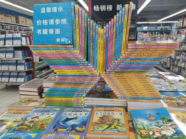 スーパーの子供の本コーナー。書籍をなぜに器用にX字型に積むのか